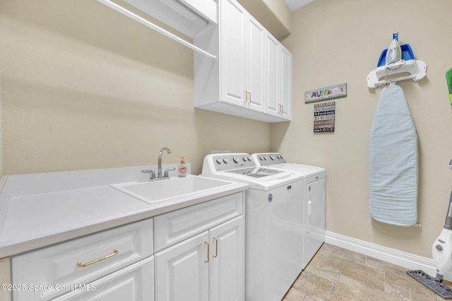 washroom featuring washer and clothes dryer, a sink, stone finish flooring, cabinet space, and baseboards