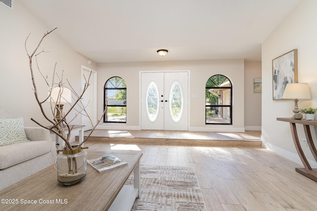 foyer entrance with a wealth of natural light, french doors, baseboards, and wood finished floors