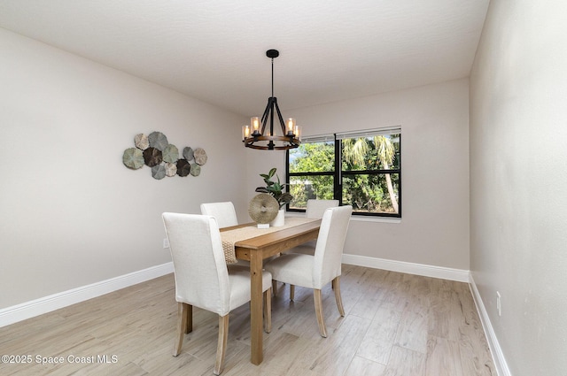 dining space with an inviting chandelier, light wood-style flooring, and baseboards