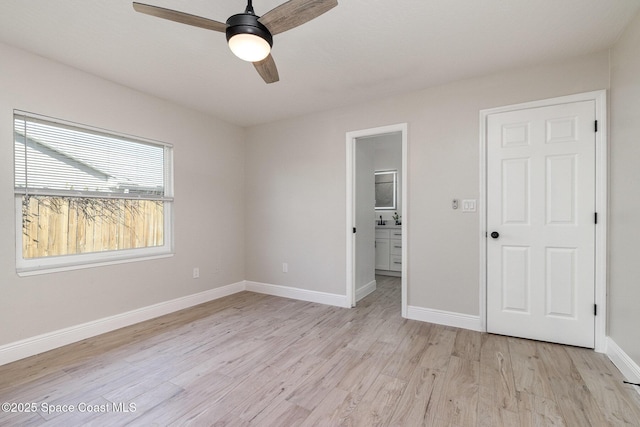 unfurnished bedroom featuring baseboards, ensuite bathroom, light wood-style floors, and a ceiling fan