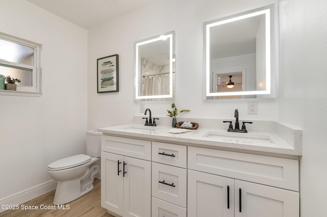 full bath featuring double vanity, wood finished floors, toilet, and a sink