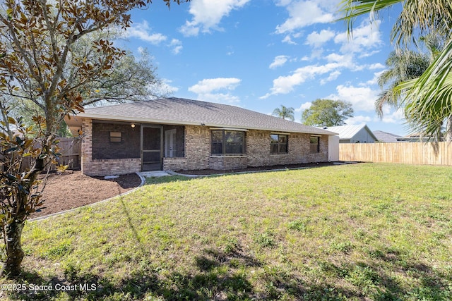 back of house with a lawn, brick siding, a fenced backyard, and roof with shingles