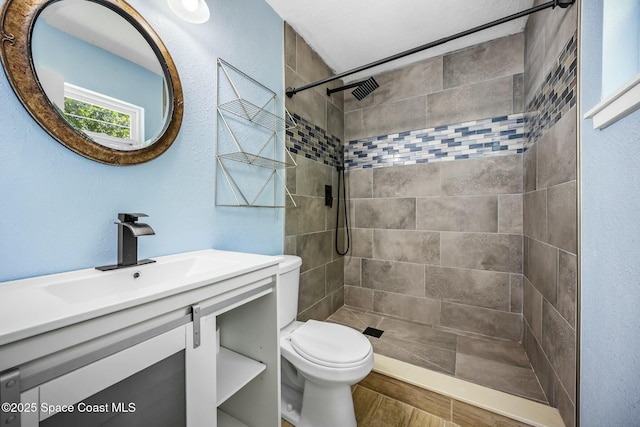 bathroom featuring vanity, toilet, and a tile shower