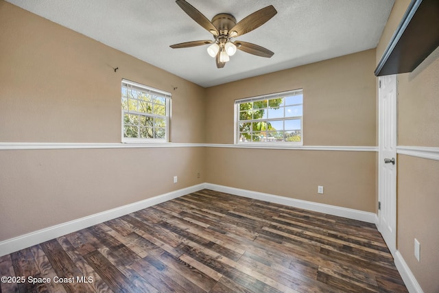 spare room with dark wood finished floors, a textured ceiling, and baseboards