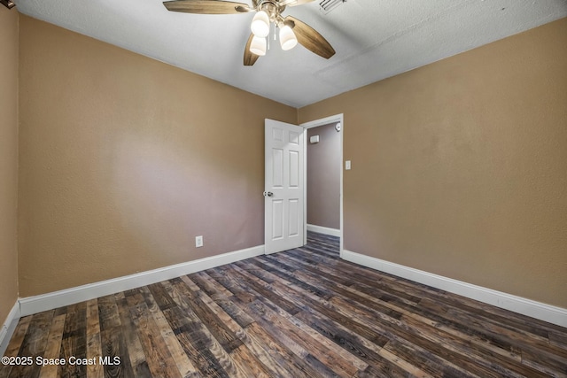 unfurnished room featuring dark wood finished floors, a ceiling fan, and baseboards