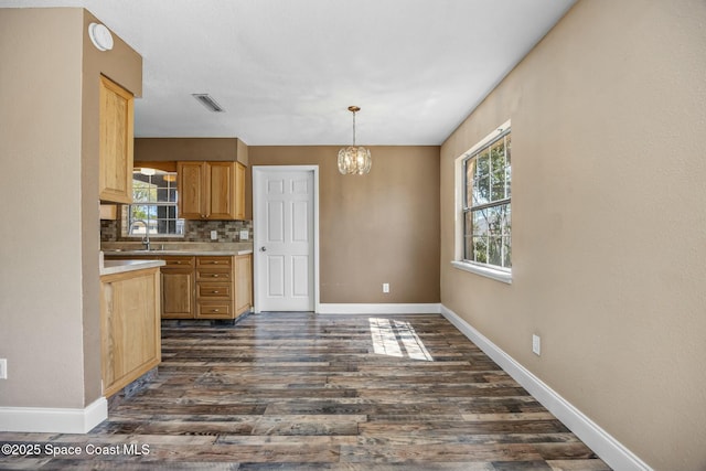 kitchen with visible vents, dark wood finished floors, light countertops, decorative backsplash, and an inviting chandelier