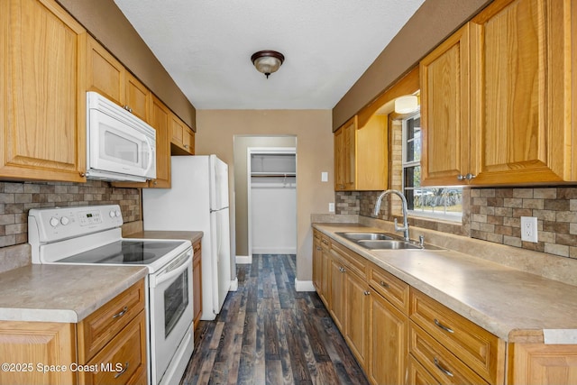 kitchen with a sink, baseboards, white appliances, and light countertops