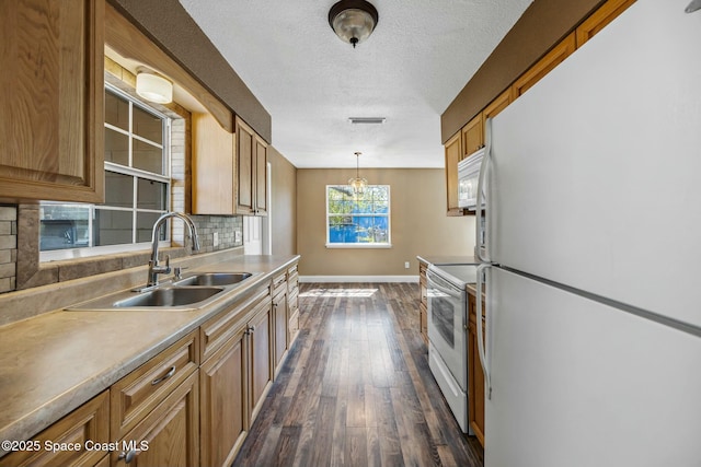 kitchen with a sink, backsplash, dark wood finished floors, white appliances, and baseboards