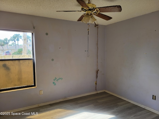 spare room with a ceiling fan, wood finished floors, baseboards, and a textured ceiling