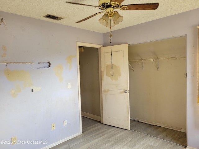 unfurnished bedroom featuring a closet, visible vents, light wood-style flooring, and a textured ceiling