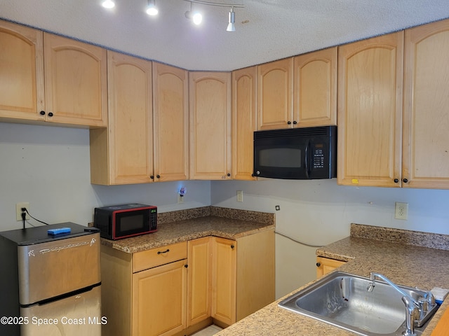 kitchen featuring light brown cabinetry, stainless steel refrigerator, black microwave, and a sink