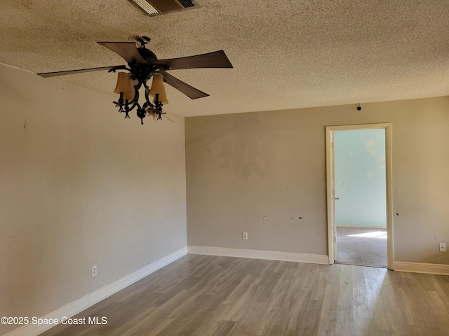 empty room with visible vents, ceiling fan, baseboards, wood finished floors, and a textured ceiling