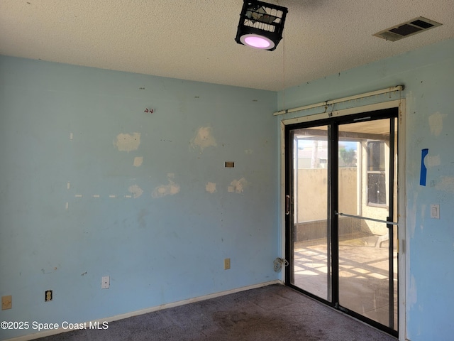 carpeted spare room with visible vents, a textured ceiling, and baseboards