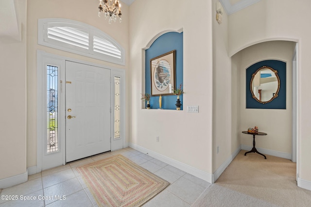 tiled entryway with a chandelier, a high ceiling, and baseboards