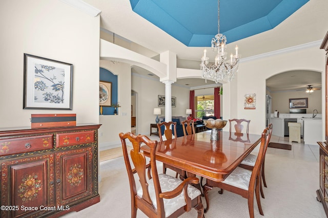 dining room featuring arched walkways, ornate columns, ceiling fan with notable chandelier, and a tray ceiling