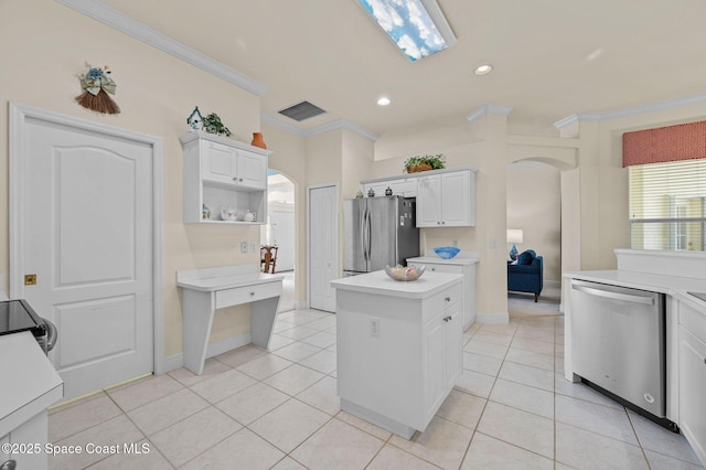 kitchen with arched walkways, appliances with stainless steel finishes, light countertops, and ornamental molding