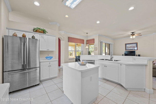 kitchen with a sink, a kitchen island, stainless steel appliances, light countertops, and light tile patterned floors