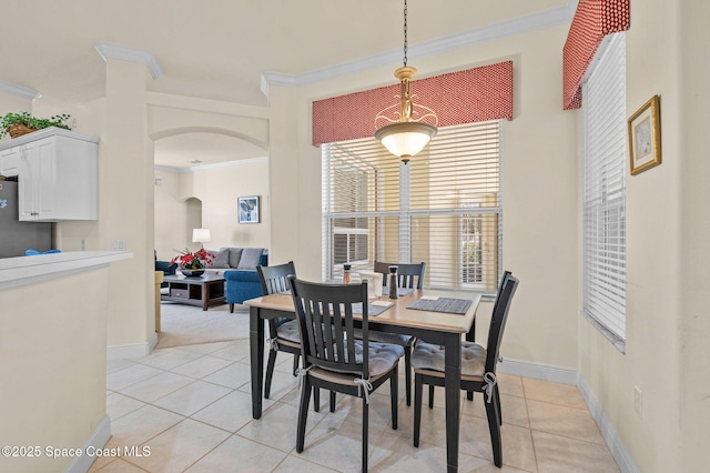 dining room featuring baseboards, arched walkways, light tile patterned flooring, and crown molding