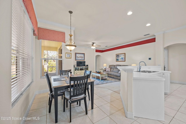 dining space featuring ceiling fan, arched walkways, light tile patterned flooring, and crown molding