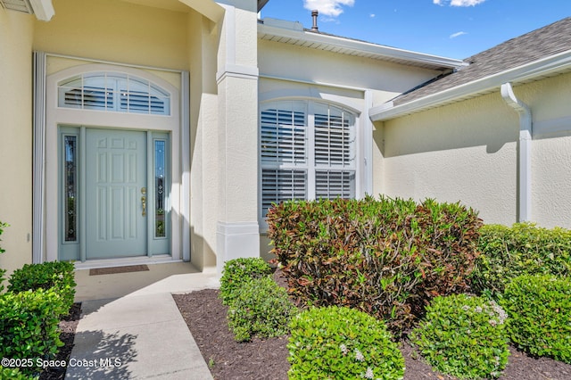 doorway to property with a shingled roof and stucco siding