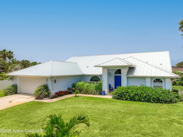 view of front of house with a front yard, a standing seam roof, stucco siding, a garage, and metal roof