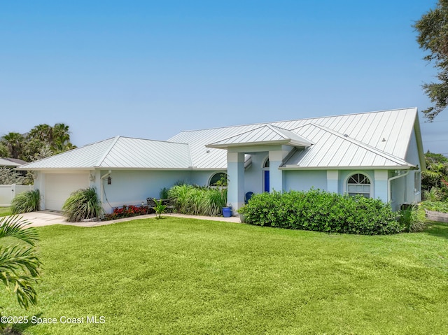 view of front of home with a standing seam roof, a front lawn, an attached garage, and stucco siding