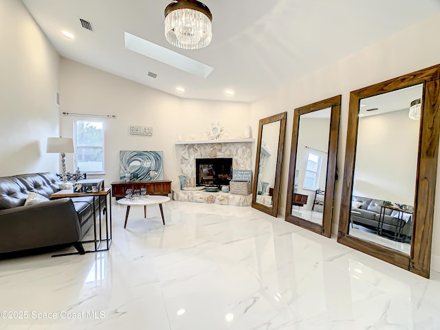 living area with visible vents, lofted ceiling with skylight, marble finish floor, a glass covered fireplace, and recessed lighting