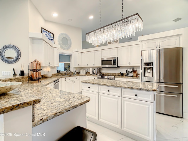 kitchen featuring white cabinetry, a peninsula, stainless steel appliances, and light stone countertops