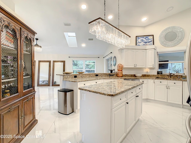 kitchen featuring visible vents, marble finish floor, light stone counters, a kitchen island, and a peninsula