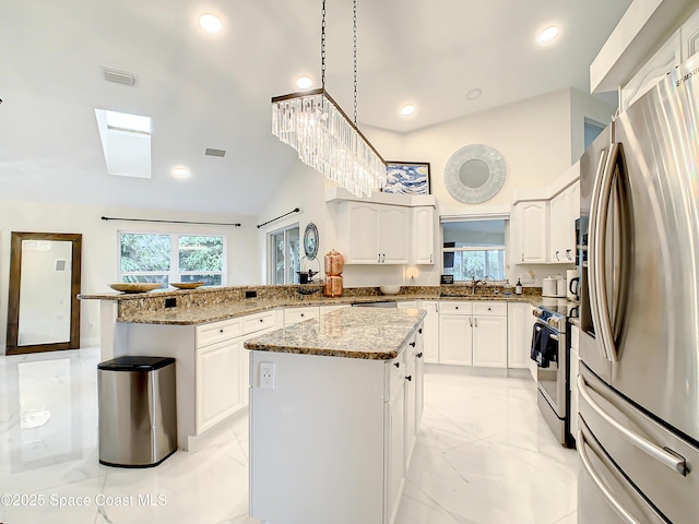 kitchen featuring visible vents, marble finish floor, a kitchen island, appliances with stainless steel finishes, and a peninsula