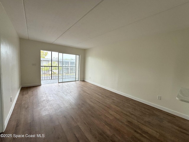 unfurnished room featuring dark wood-style floors and baseboards