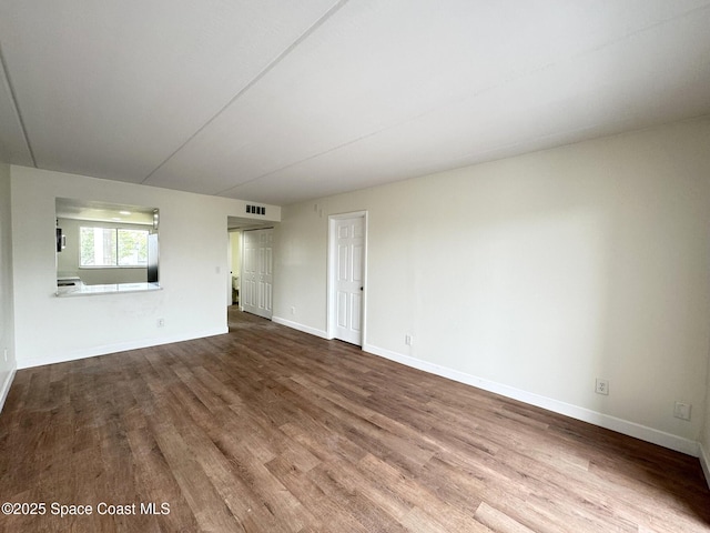 unfurnished living room featuring wood finished floors, visible vents, and baseboards