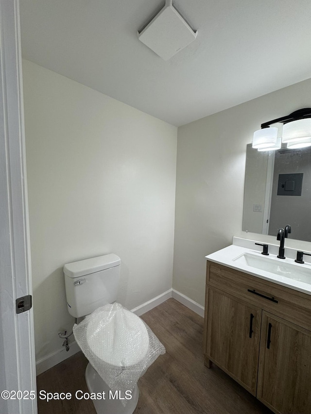 bathroom featuring vanity, toilet, wood finished floors, and baseboards