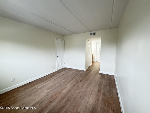 spare room with visible vents, baseboards, and dark wood-style flooring