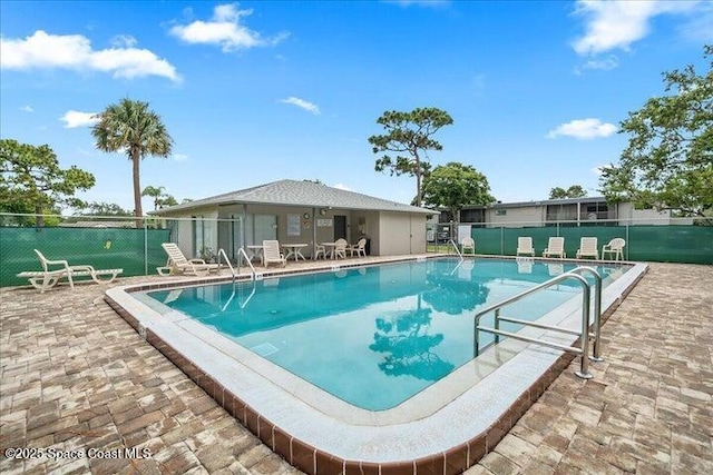 community pool with a patio area and fence