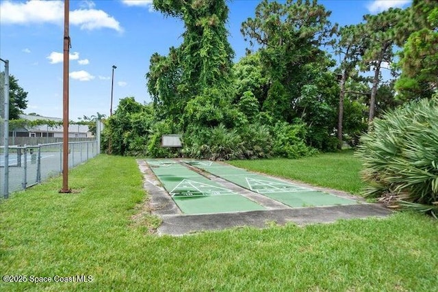 surrounding community featuring shuffleboard, a lawn, and fence