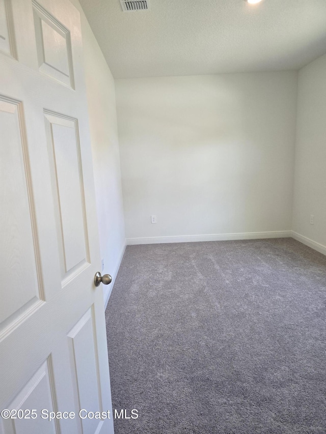 carpeted empty room featuring baseboards, visible vents, and a textured ceiling