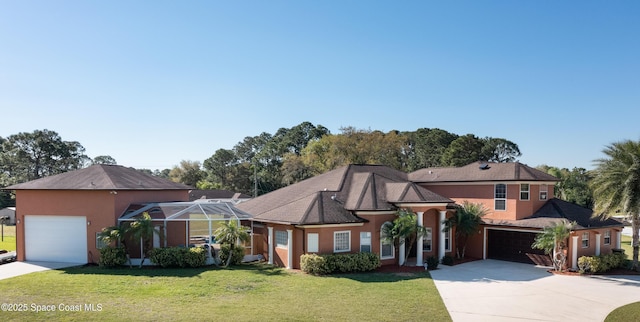 view of front of property with stucco siding, concrete driveway, glass enclosure, and a front yard