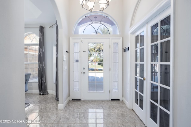 foyer featuring a notable chandelier, baseboards, and arched walkways