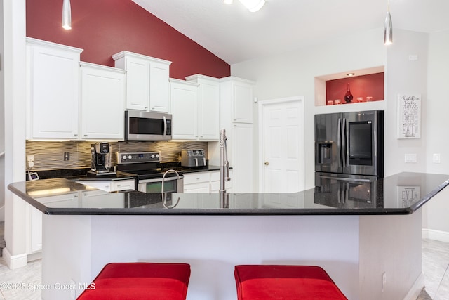 kitchen with backsplash, a kitchen bar, vaulted ceiling, appliances with stainless steel finishes, and white cabinetry