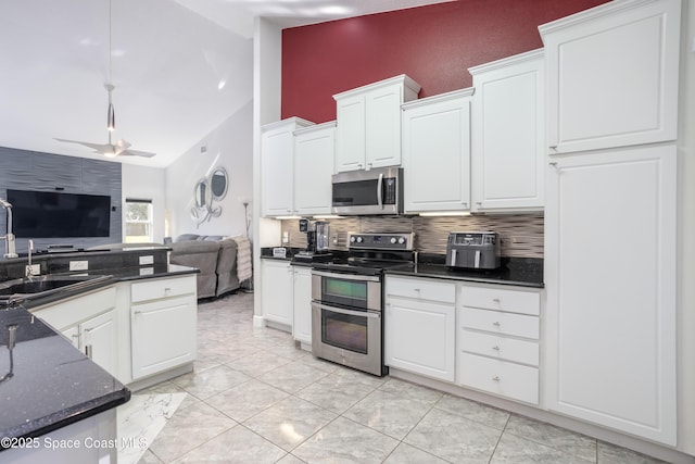 kitchen featuring lofted ceiling, a sink, decorative backsplash, appliances with stainless steel finishes, and open floor plan