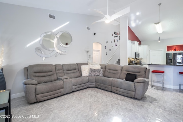 living area featuring arched walkways, visible vents, and baseboards