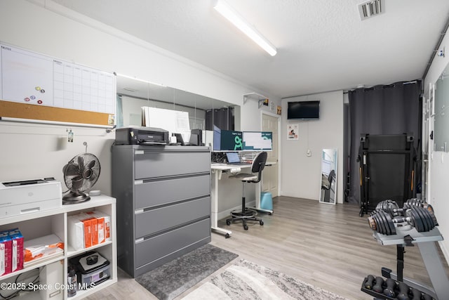 home office with wood finished floors, visible vents, and a textured ceiling