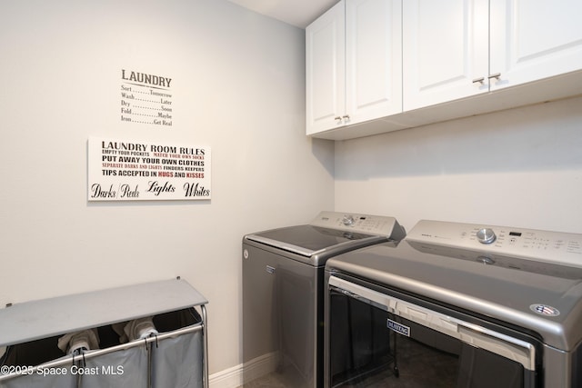 washroom featuring cabinet space, baseboards, and separate washer and dryer