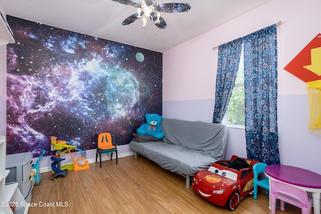 playroom with a ceiling fan, baseboards, and wood finished floors