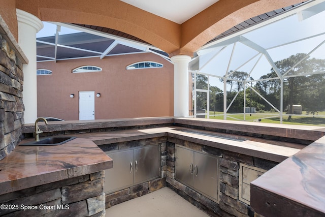 view of patio / terrace with area for grilling, glass enclosure, and a sink