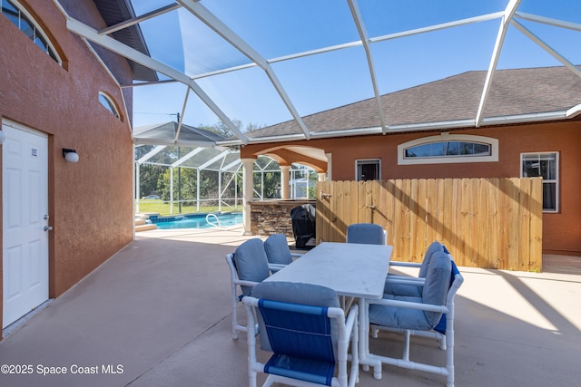 view of patio with a lanai, outdoor dining space, an outdoor pool, and fence