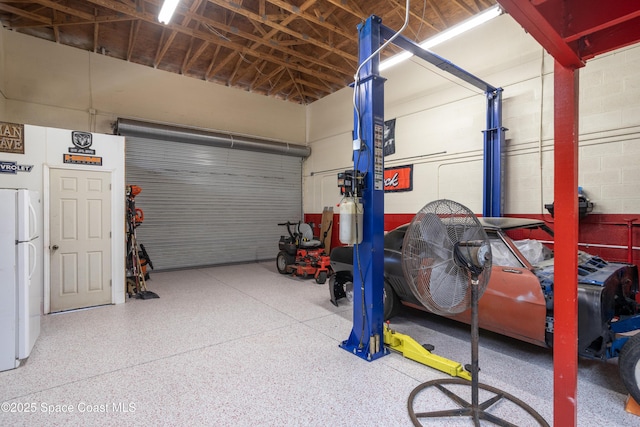 garage with concrete block wall and freestanding refrigerator