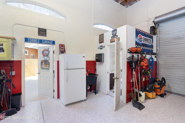 garage featuring concrete block wall and freestanding refrigerator