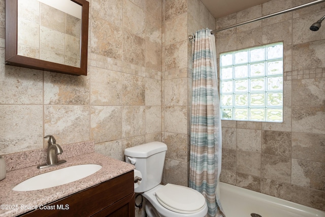 full bathroom with tiled shower, toilet, and vanity